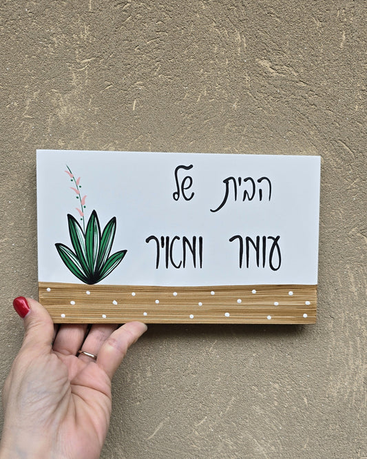 שלט לדלת כניסה עם צמח ירוק וכיתוב אישי בעבודת יד על בסיס עץ טבעי