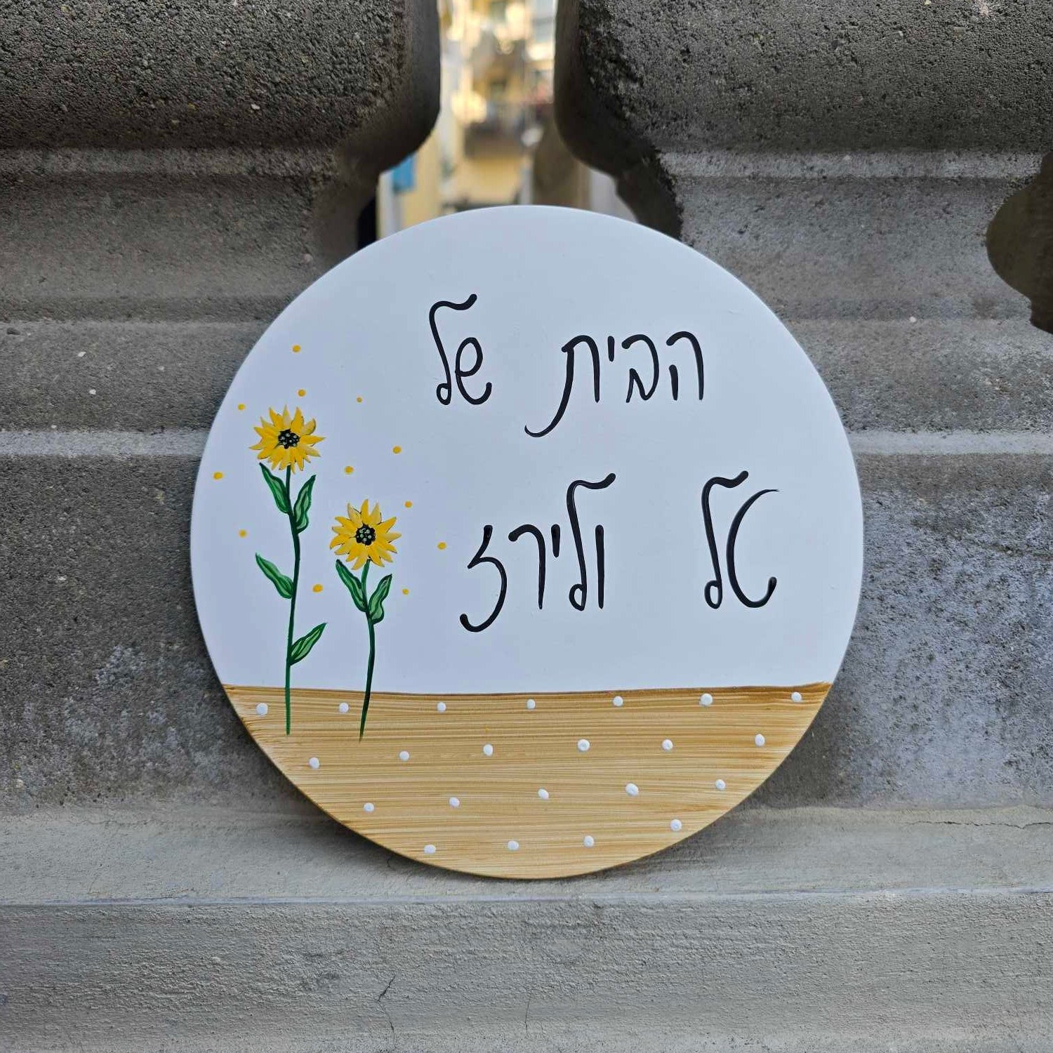 שלט לדלת כניסה עגול עם חמניות מצוירות בעבודת יד על רקע לבן עם פס עץ טבעי