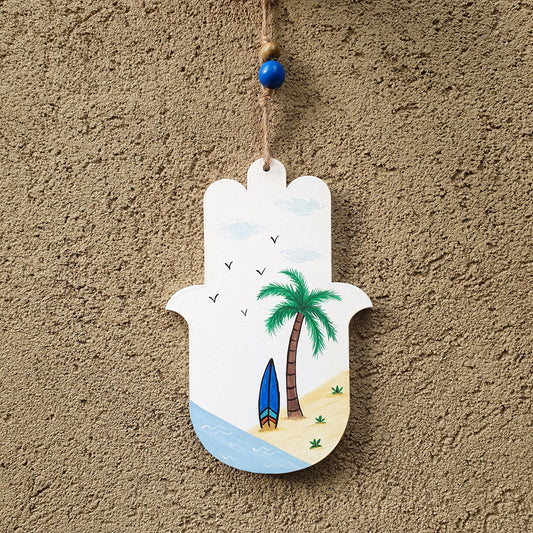 חמסה מעוצבת לקיר בעבודת יד עם ציור דקלים וים תלויה על דלת כניסה לבית באור טבעי