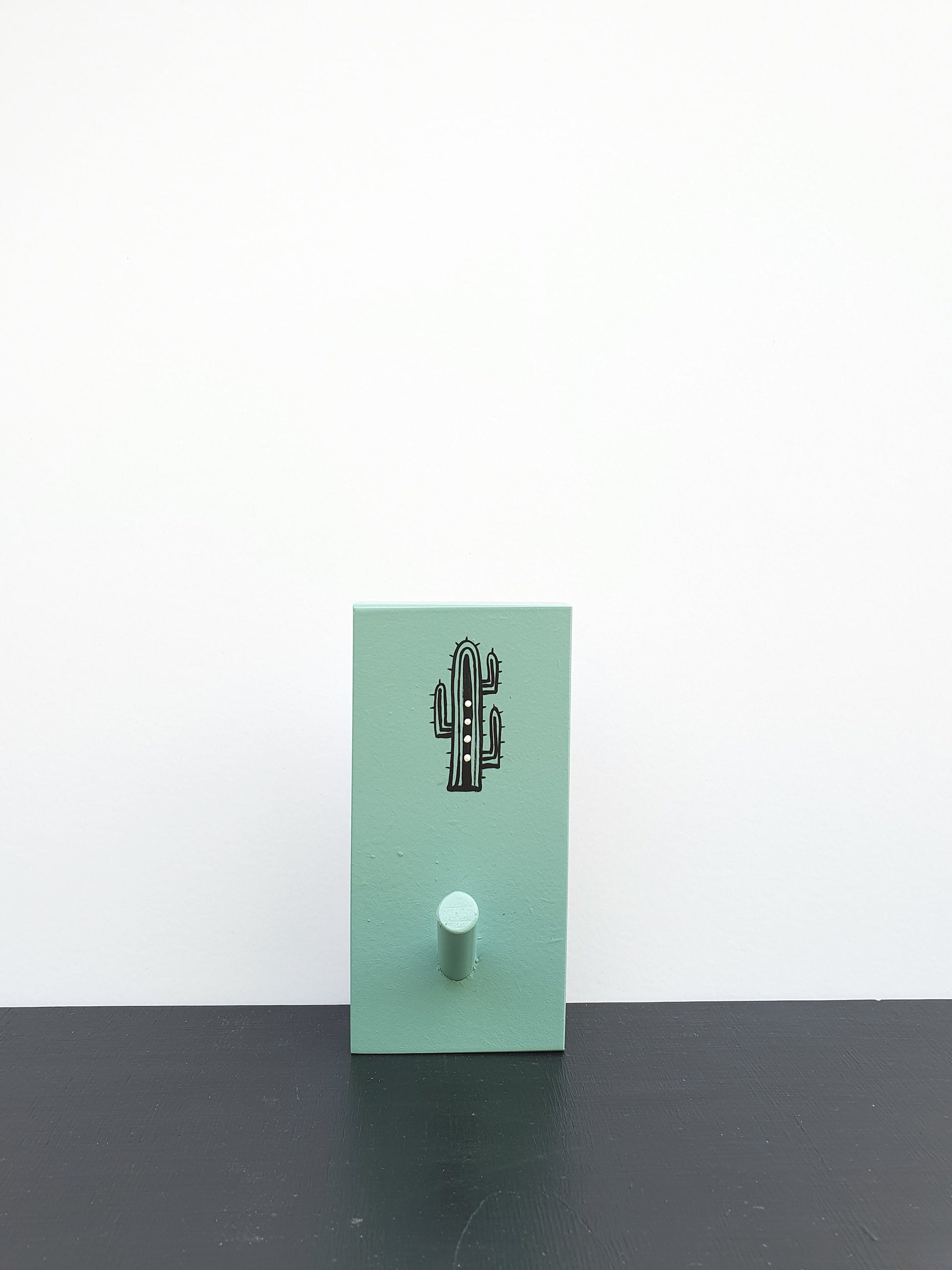 מתלה עץ עם וו תלייה מצויר בעבודת יד קקטוס שחור עם נקודות ירוקות על רקע לבן מתלה לבגדים תיקים ומגבות לכניסה לבית חדר רחצה וחדר ילדים עיצוב נקי מודרני